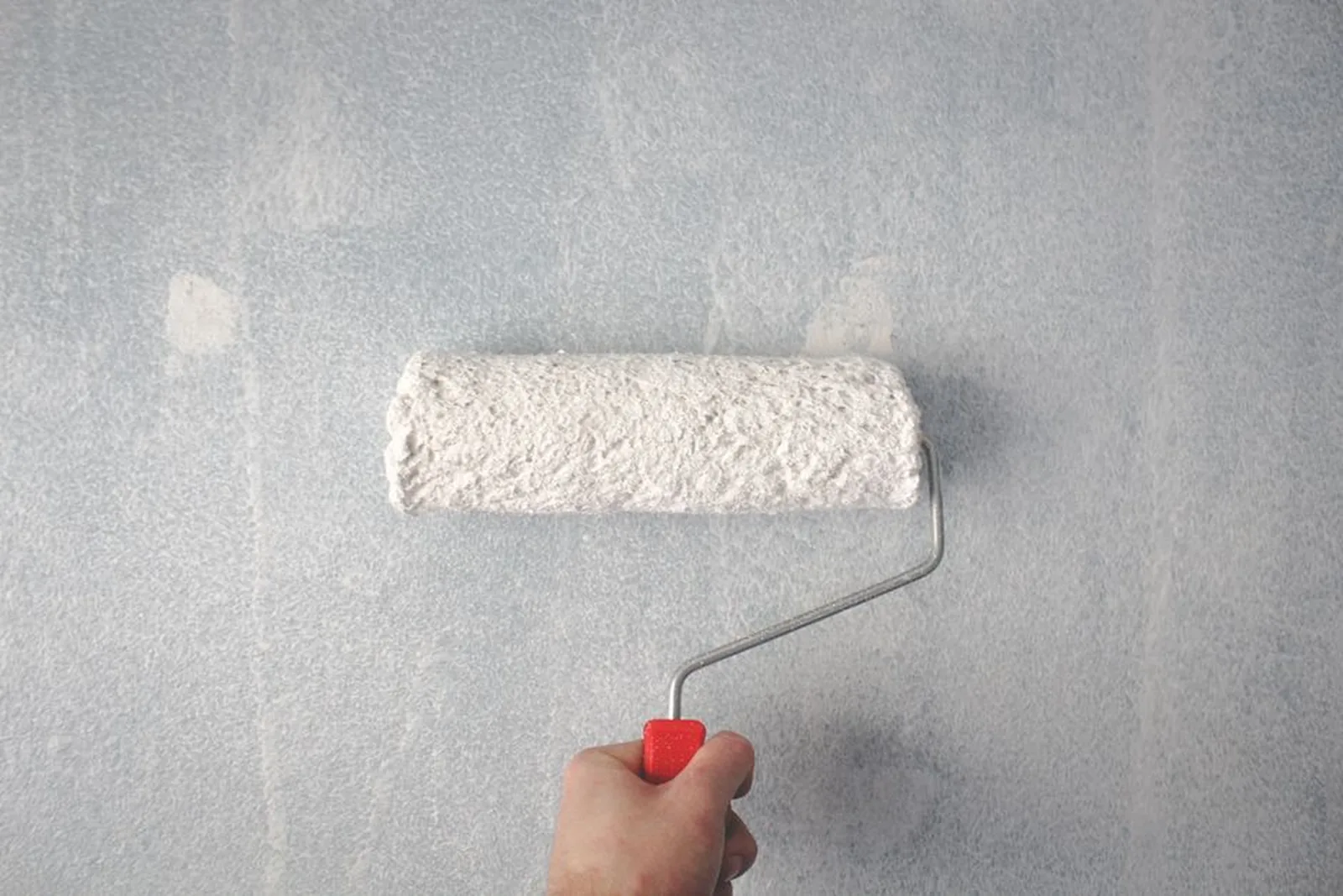Peintre appliquant une peinture claire au rouleau sur un mur
